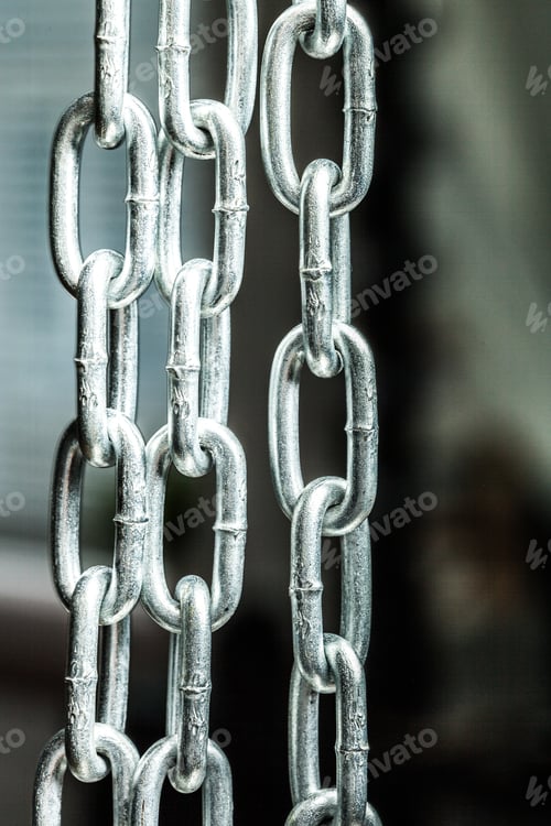 Preview: Close-up view of linked metal chains in an indoor setting with soft lighting