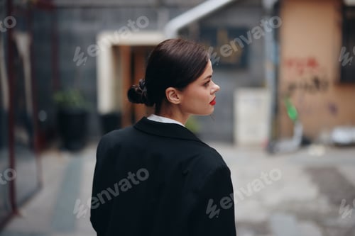 Preview: Stylish woman in a black jacket walks along the city street with her back to the camera, follow me
