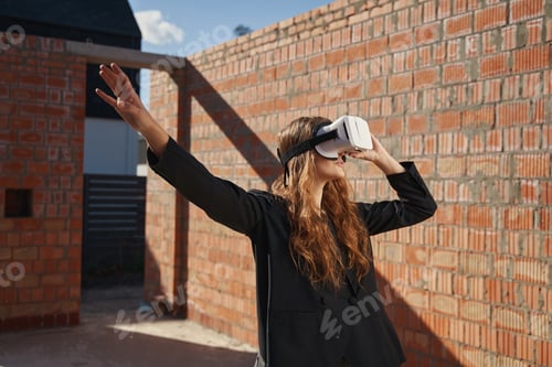 Preview: Woman worker looking through VR glasses and stretching out arm