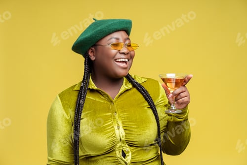 Preview: Happy African American woman drinking cocktail looking away isolated. Toast, party concept