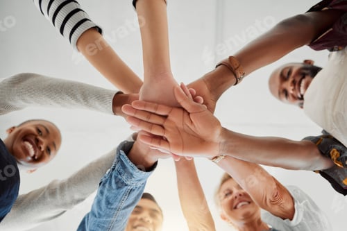 Preview: Group of happy clothing designers stacking their hands together in a shop at work. Tailors having f