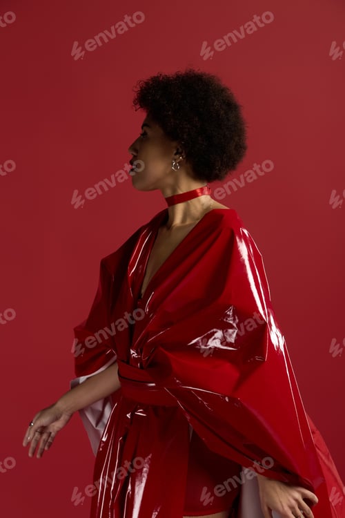 Preview: Stunning young woman showcases elegant fashion against vibrant red backdrop