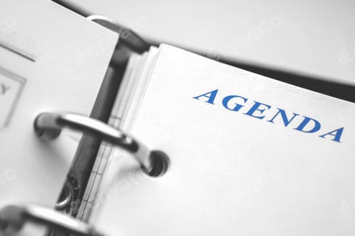 Preview: Daily agenda paper planner closeup. Black and white picture with blue word Agenda in focus