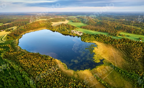 Preview: a lake surrounded by lush green forest under a cloudy sky