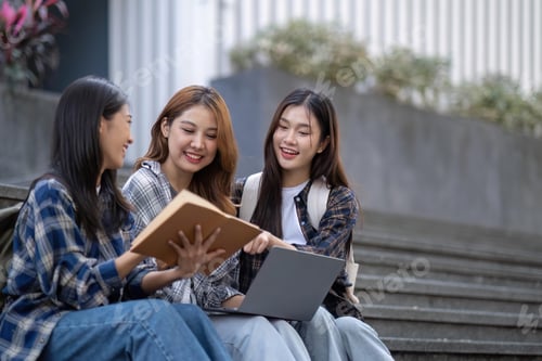 Preview: Nice young students use laptop after class sitting outdoors. girls wear casual clothes in spring
