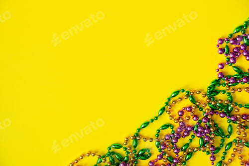 Preview: Mardi Gras concept. Multicolored beads on yellow background. Festive carnival symbols.