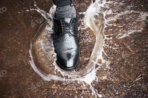 Preview: Be careful not to fall. Shot of a unrecognizable man walking in a puddle of water outside.