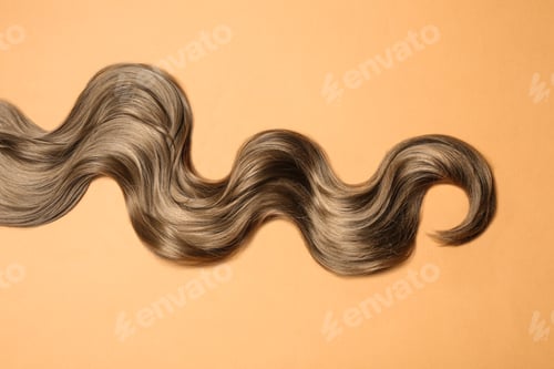 Preview: Lock of brown wavy hair on color background, top view