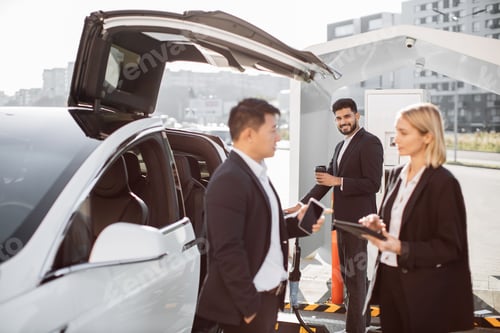 Preview: Multiethnic coworkers waiting at EV charging point
