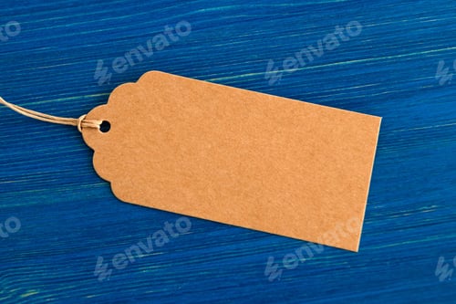 Preview: Brown blank paper price tag or label set on the blue wooden background, closeup.