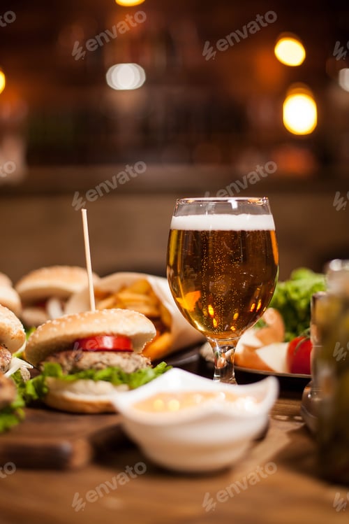Preview: Golden beer next to delicious burgers on wooden table