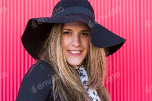 Preview: portrait of a beautiful young woman with a stylish hat, she is smiling. Red background