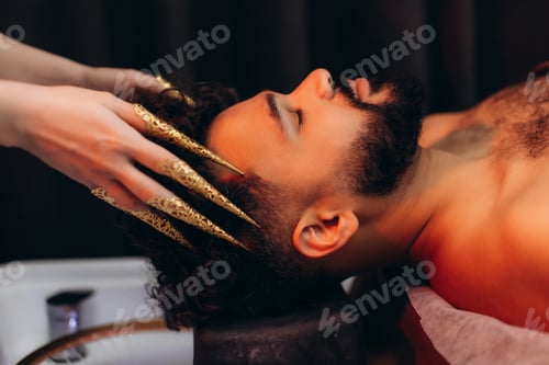 Preview: Man receiving surreal head massage with golden nail rings