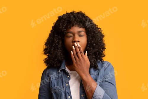 Preview: African american woman yawning on yellow, covering mouth with hand
