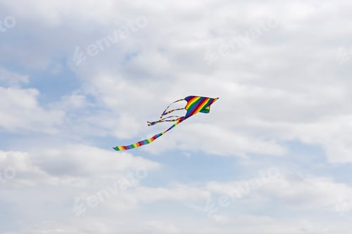 Preview: Colorful blue sky with white fluffy clouds and a flying colored kite