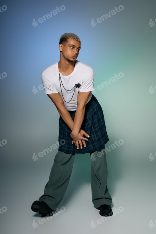 Preview: Stylish young man with dyed hair showcases unique fashion statement in studio setting