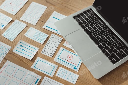 Preview: High angle view of ux app development sketches and laptop on wooden table