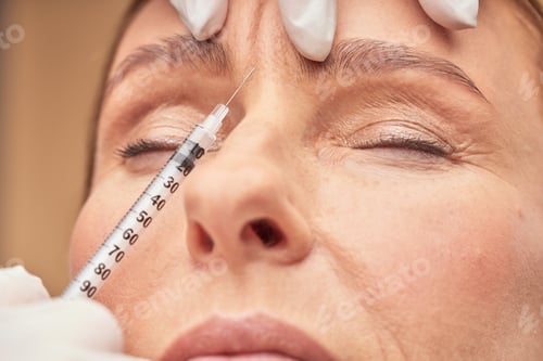Preview: Anti Aging procedures. Close up shot of beautician in protective gloves making cosmetic injection in