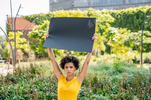 Visualização: Jovem étnica séria demonstrando banner preta em branco no parque