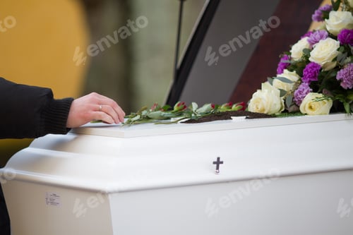 Preview: Closeup shot of a person hand on a casket with a blurred background