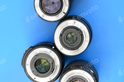 Preview: Several photographic lenses lie on a bright blue background. Space for text
