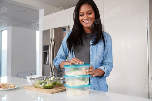 Preview: Woman In Kitchen Preparing High Protein Meal And Putting Portions Into Plastic Containers