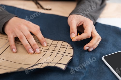 Preview: Cropped view of african american designer holding needle near sewing print and cloth
