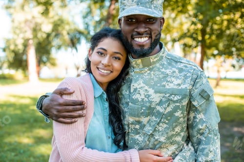 Preview: smiling african american soldier in military uniform hugging girlfriend in park