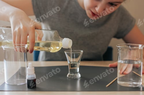Preview: School girl filling a glass with oil preparing for a science chemical experiment. Back to school. N