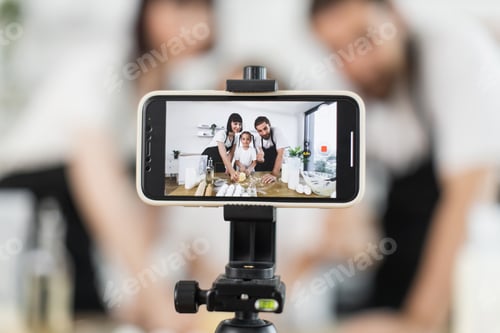 Preview: Caucasian family filming cooking video kneading dough in professional kitchen