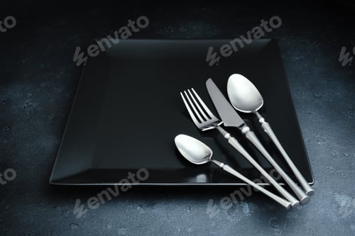 Preview: Cutlery and black square dish on dark textured background. Table setting
