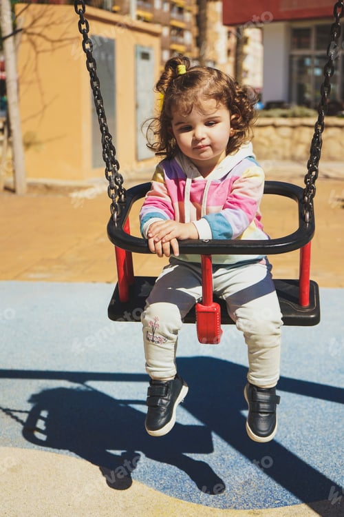 Preview: Young little girl playing in a swing at the park