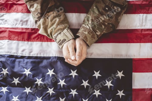 Preview: American soldier mourning and praying with the American flag in front of him