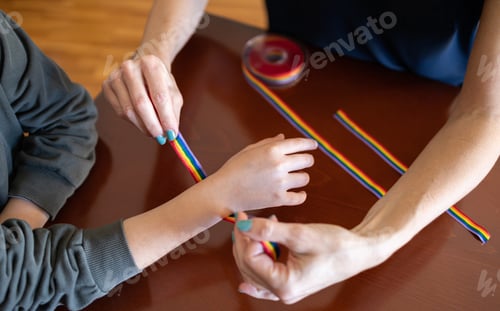 Preview: Woman putting a LGBT rainbow bracelet on a young girl's wrist