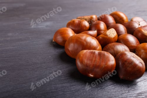 Preview: pile of sweet chestnuts on black wooden background