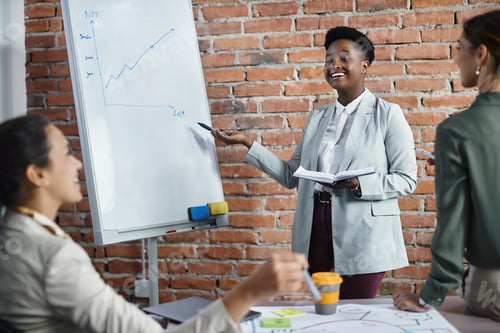 Preview: Happy black CEO giving business presentation to her colleagues in the office.