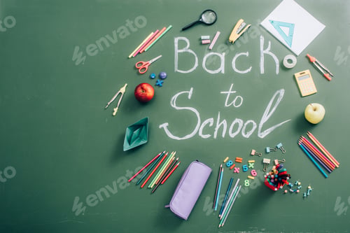 Preview: top view of school supplies and whole apples near back to school lettering on green chalkboard