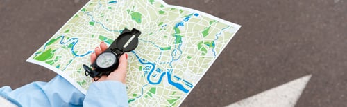 Preview: panoramic shot of woman holding map and compass on street