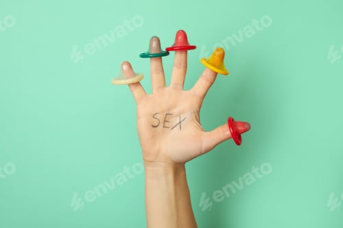 Preview: Female hand with text Sex and condoms on fingers on mint background