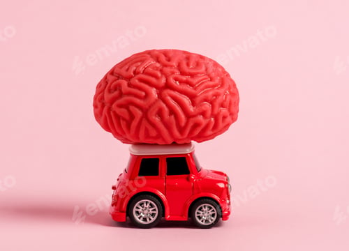 Preview: Miniature red car carries a model of a human brain on the roof on a pink background.