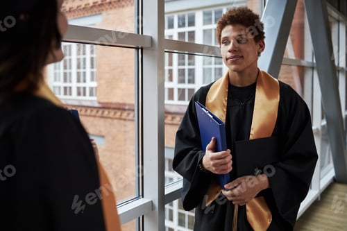 Preview: Young Black Man Wearing Graduation Gown Talking with Fellow Student