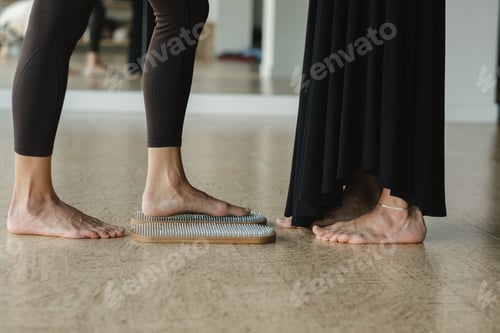 Preview: close-up of the legs of girls engaged in standing on a board with nails barefoot