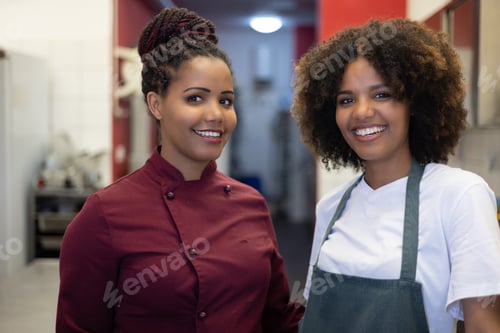 Preview: Portrait of colleagues in the kitchen smiling and looking at the camera. African cook and waitress.