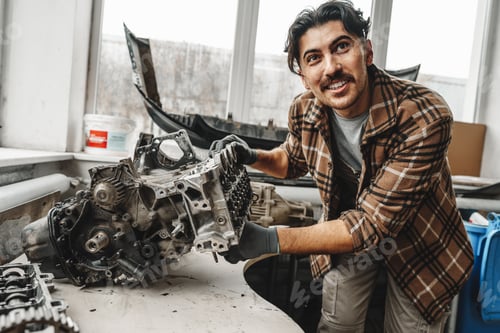 Preview: Workman disassembling car engine at the working table of the car service garage