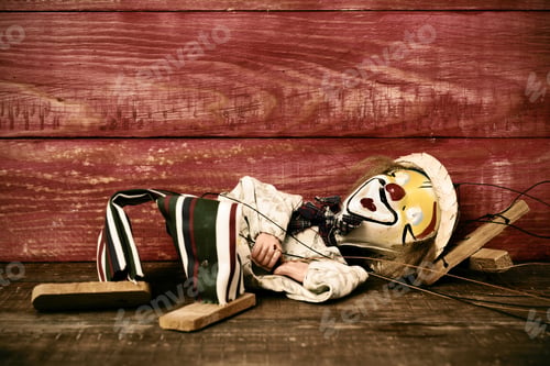 Preview: An Old Marionette With Its Face Painted Like A Clown Dropped On A Rustic Wooden Surface, With A
