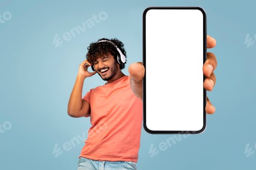 Preview: Cool eastern guy singing and dancing on blue, showing smartphone