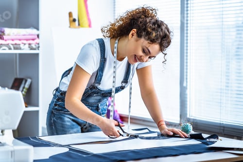 Preview: The cute tailor sews a dress on the table
