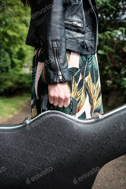 Preview: Close up of woman arm holding a guitar case in a park.