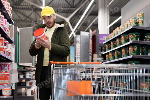 Preview: the buyer chooses paint for interior work in the store of finishing materials