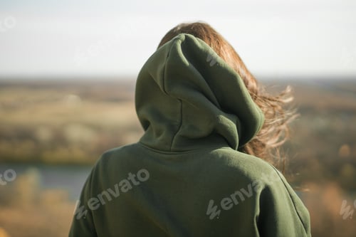 Preview: Rear view of trendy young woman in dark green hoodie in autumn. Cute model walks in park in golden